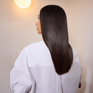 A model dressed in a white shirt showcases her sleek and shiny dark brown hair thanks to Goldwell's range.