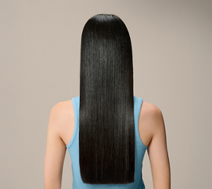 Goldwell Dualsenses Pure Hydration after image showing a person from behind with long sleek dark hair and a blue top against a neutral studio background.