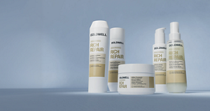 Goldwell Dualsenses Rich Repair haircare range displayed as white and gold shampoo, conditioner, treatment and spray products on a soft blue studio background.