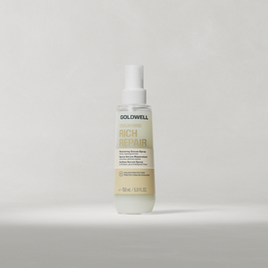 Goldwell Dualsenses Rich Repair Restoring Serum Spray bottle standing upright on a soft light grey studio background.