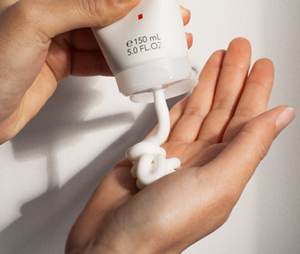 A hand squeezes the Goldwell StyleSign Curls Defining Cream (150ml) into the opposite plam, ready to condition and bundle curls for healthy-looking, nourished and defined results.