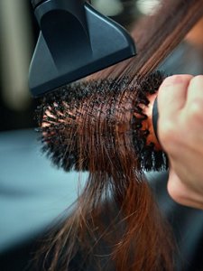  In front of a bright orange backdrop, a model shows of the sleek shine of her flowing dark hair, created thanks to Goldwell's range of products