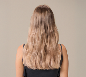 Goldwell Elumen Color After image showing the back of a model's hair following use of Goldwell's Dualsenses Bond Pro range, displaying visibly stronger, smoother and healthier-looking results after image showing the back of a model with smooth, glossy, warm blonde hair against a neutral beige background.