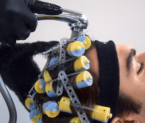 A Goldwell Master Texture specialist rinses a client's hair as it is held in place with perm clips