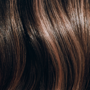 Goldwell Elumen collage medium image showing a close-up of glossy dark brunette hair with warm highlights and visible shine. 