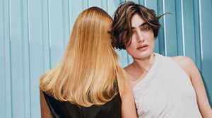 Goldwell Elumen campaign image featuring two models with blonde and dark hair in an editorial setting
