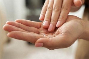 Woman warming argan oil in between her palms