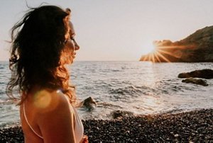 Woman with curly hair on the beach at sunset