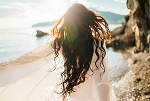 Woman with long, beachy waves walking on the beach