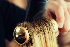 Blow-drying a section of hair with a rounded bristle brush