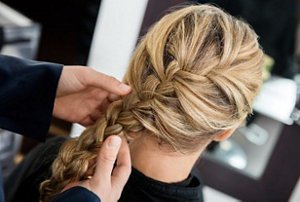 Blonde woman having her hair plaited into a pretty French braid