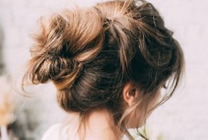 Bridesmaid with her brunette hair styled in a carefully-sculpted messy bun