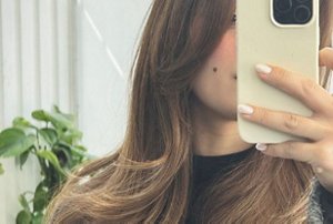 Woman taking a selfie of her butterfly cut hair