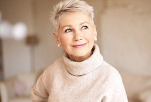 Older woman wearing a thick jumper with short, cropped blonde hair