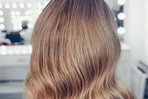 Woman with dark blonde hair styled in Hollywood waves