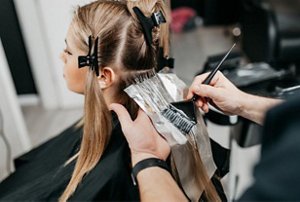 Woman at the hairdresser having bleach applied to her lengths