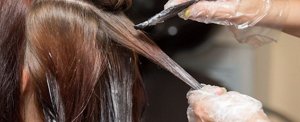 Woman having her hair dyed a shade of copper by her hairdresser