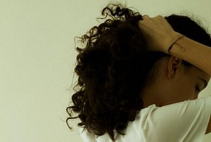 Woman with curly hair tying it back into a loose ponytail