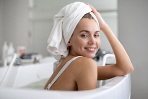 Smiling young woman with her hair wrapped in a white towel
