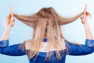 Blonde woman holding her bleached, dry hair