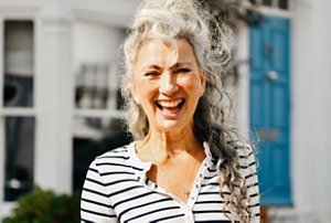 Smiling woman with long, curly natural grey hair