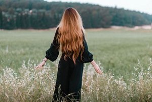 Woman with long auburn fluffy hair standing in a field
