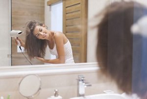Woman blow-drying her hair upside down to achieve fluffy hair