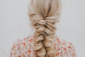 Blonde woman with thick hair plaited into a fishtail braid