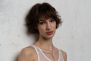 Woman wearing a white vest top with a classic French bob cut
