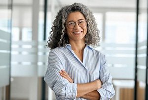 Smiling woman in her office with natural grey, curly hair