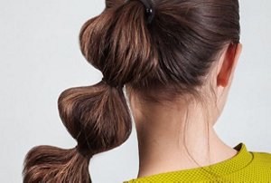 Woman wearing a green top with a bubble ponytail