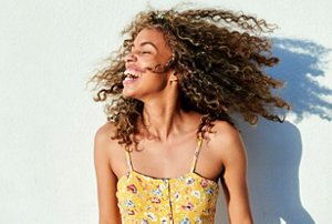 Woman with natural curly hear wearing a strappy yellow sundress
