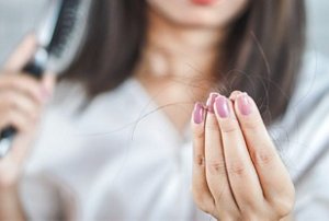 Girl examining her hairbrush for signs of hair loss