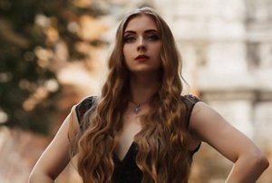 Woman in a dark gothic dress with dark makeup and mermaid waves in her hair