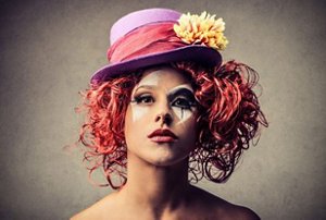 Woman wearing a clown costume for Halloween with curly red hair