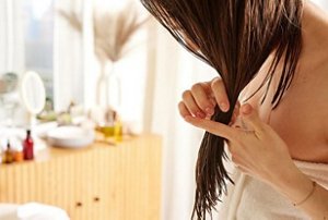 Woman applying hair serum to her damp hair