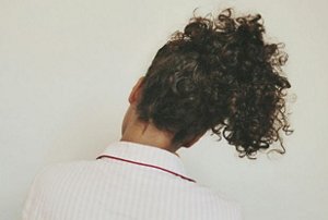 The back of a woman with her curly hair in a high ponytail