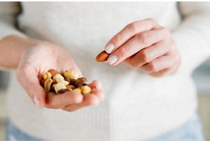 Close-up of a hand holding a variety of nuts and seeds