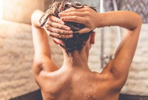 Woman applying a lamellar water rinse in the shower