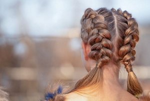 Woman with thick hair plaited into Dutch braids