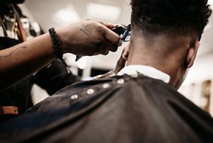 Barber using clippers on the sides of a man's head