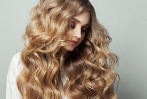 Woman with long, thick beige blonde hair styled in mermaid waves