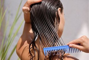 Woman combing protective moringa oil through her hair