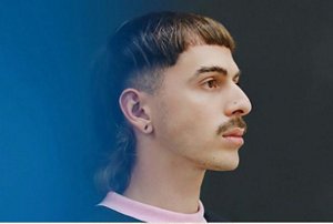 Man with a moustache and a long, tapered mullet with a blunt cut fringe