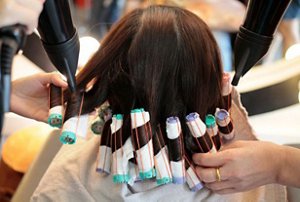 Woman having her hair permed with rods at the hairdressers