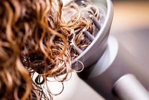 Close-up of using a diffuser to carefully dry permed hair