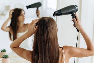 New mother drying her long brown hair with a hairdryer