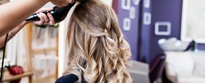 Woman with long, balayaged hair getting a root smudge at the hairdressers