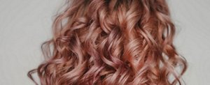 Woman with long, curled rose gold hair 