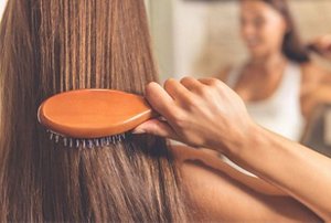 Woman gently brushing her hair with a soft hairbrush